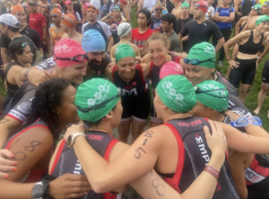 Triathletes huddling before race, wearing swim caps.
