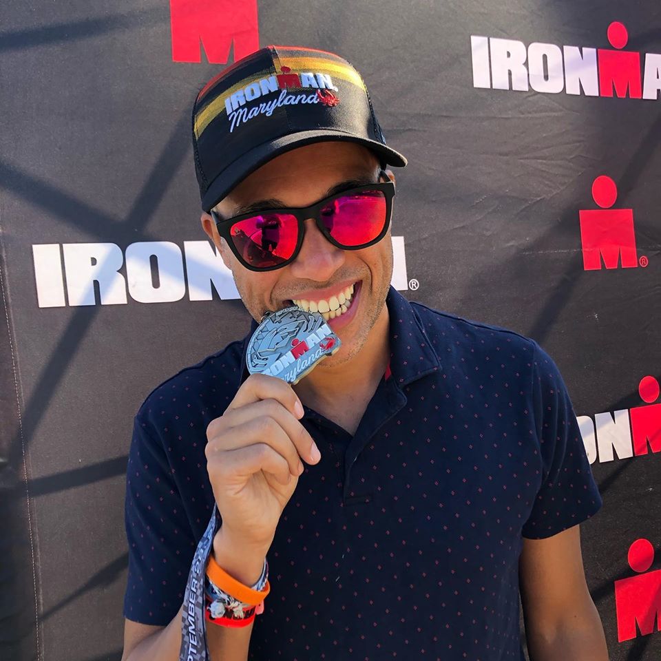 A man wearing sunglasses and holding onto a medal