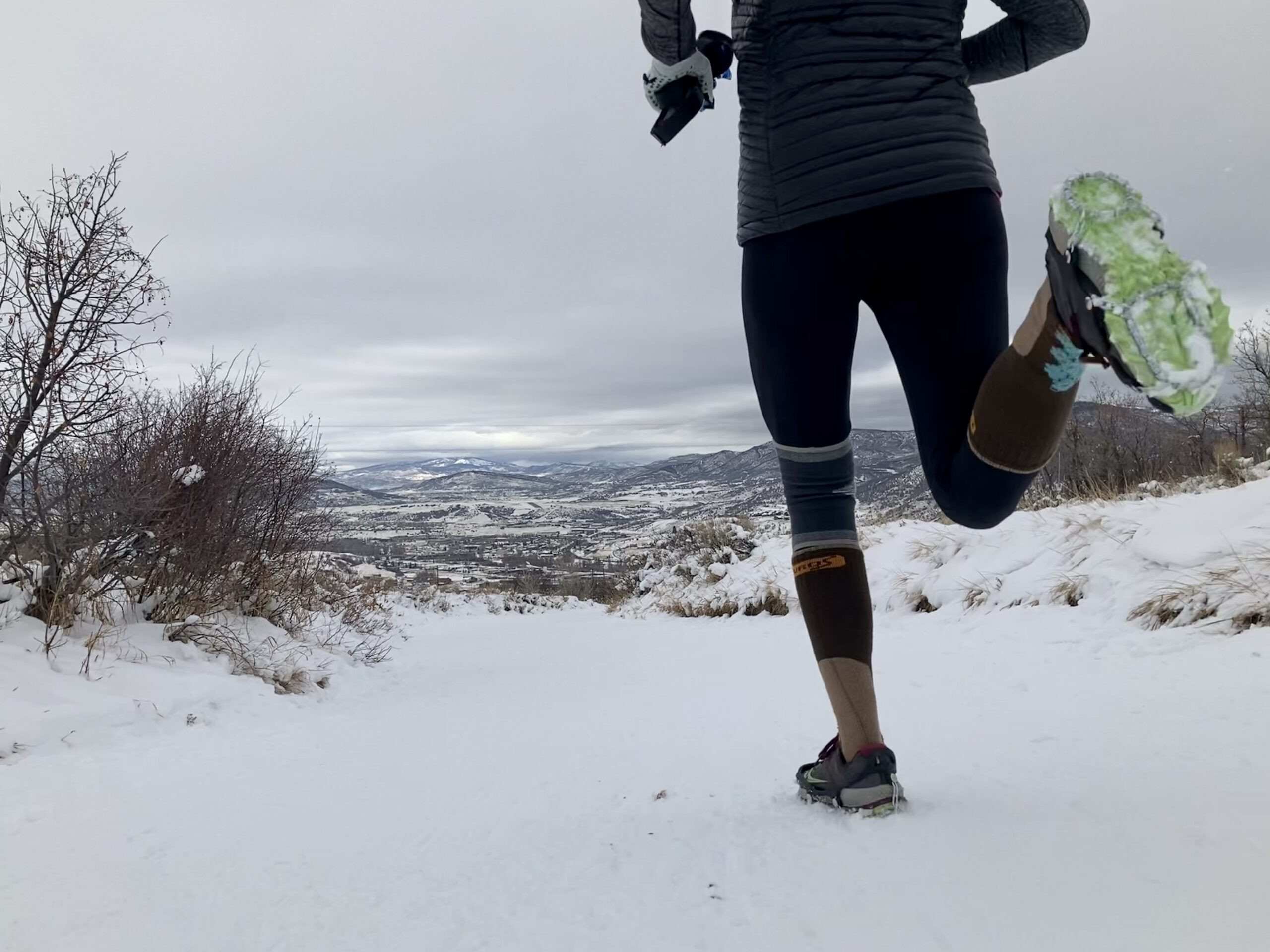 A person running in the snow on a cloudy day.