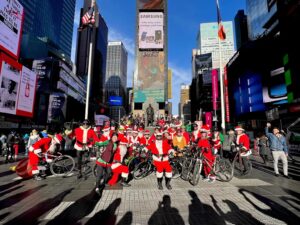 Cyclists dressed as Santa in city square.