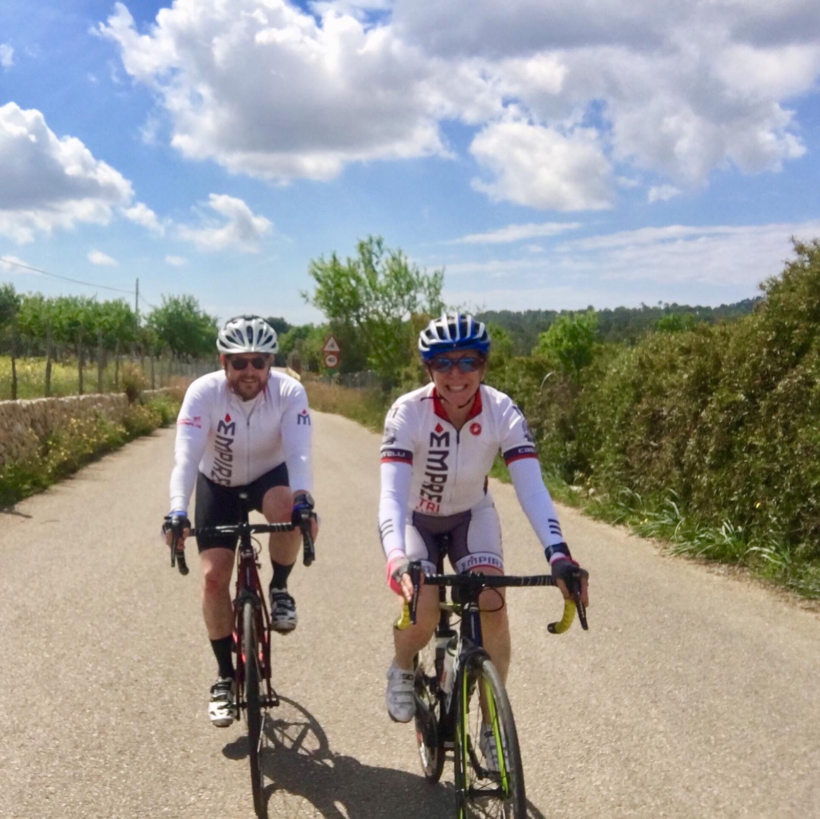 Two people riding bikes on a dirt road.