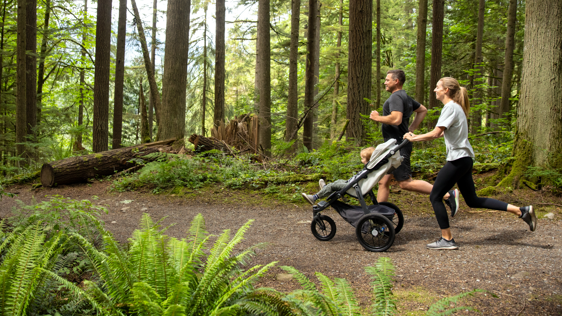 A man and woman running with a baby stroller.