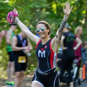 Triathlete celebrates with arms raised, smiling.